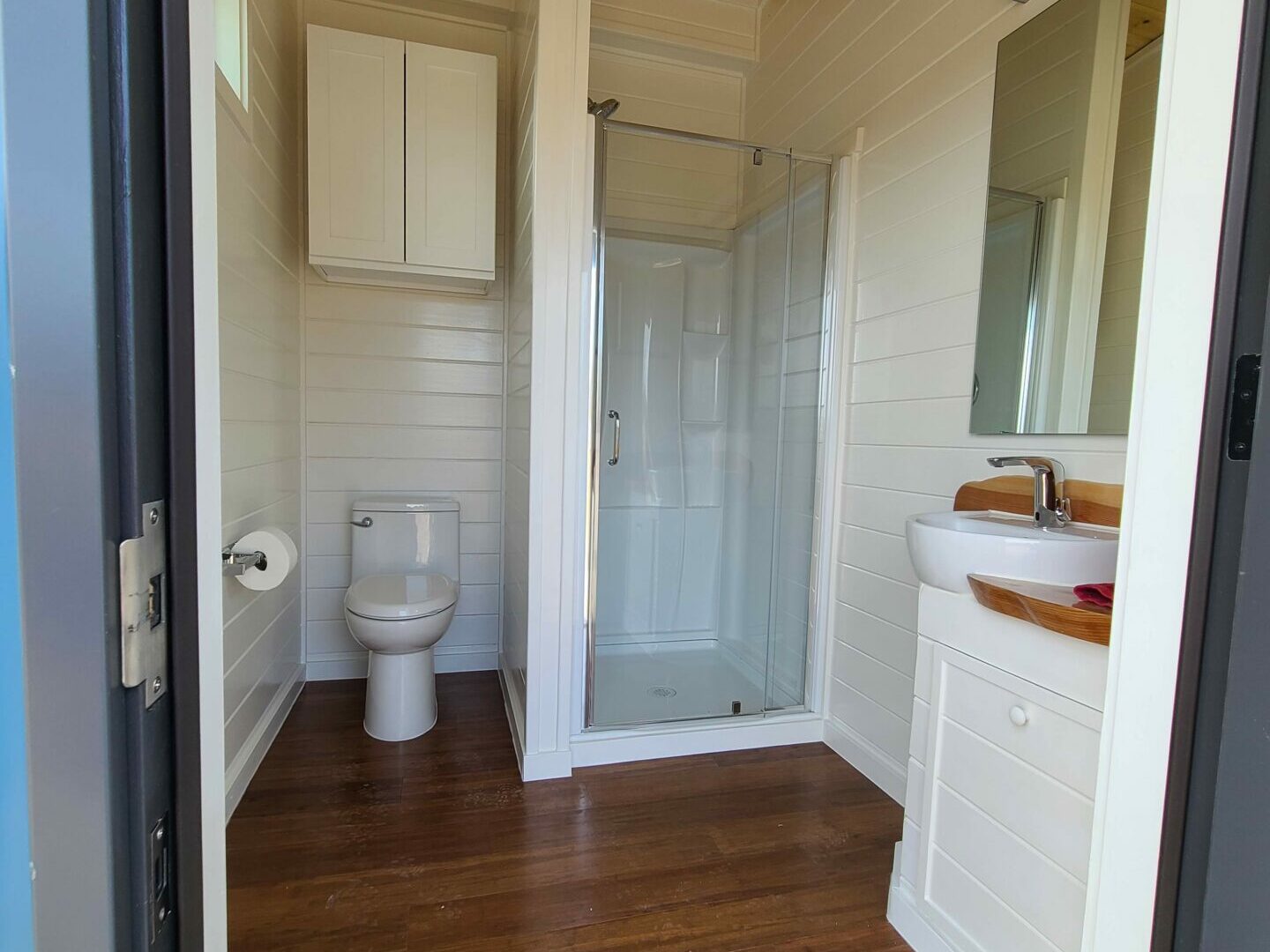 Clean private bathhouse stall at High Camp with glass shower, toilet, and vanity