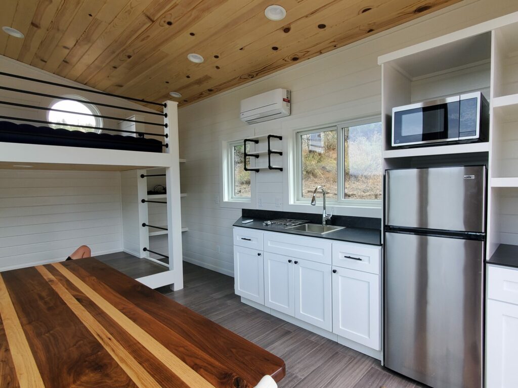 High Camp cabin interior showing full kitchen, bunk bed, and porthole window