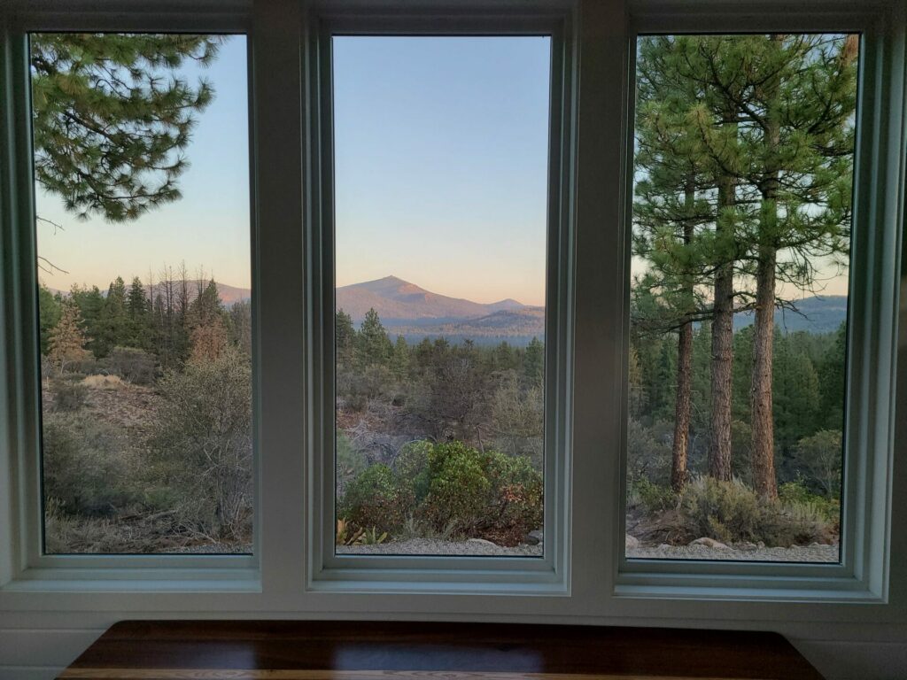 Mountain views at sunrise framed through the large windows of a High Camp cabin