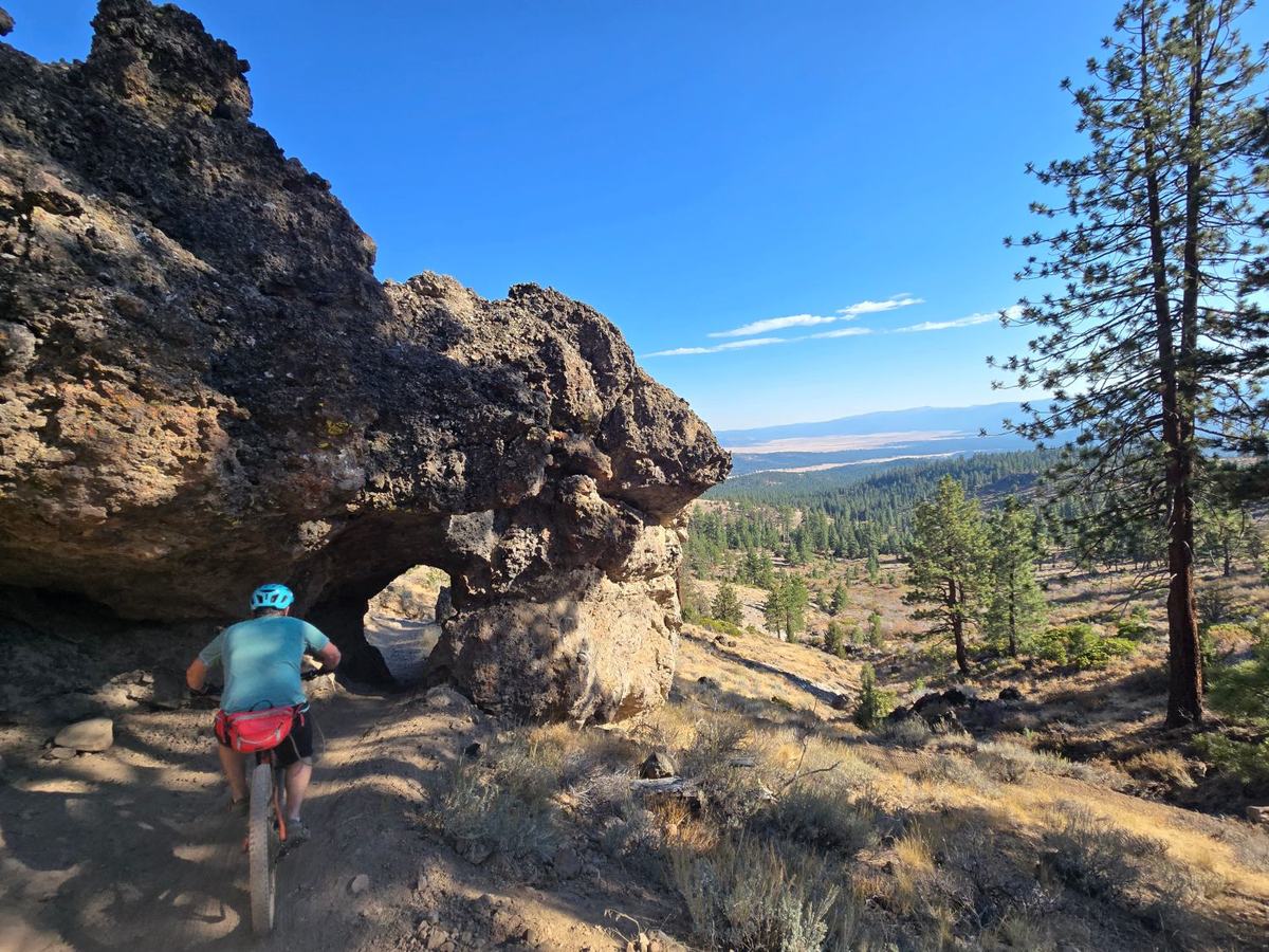 Mountain biker riding toward the rock tunnel on the Beckwourth Peak Trail, with the Sierra Valley in the distance