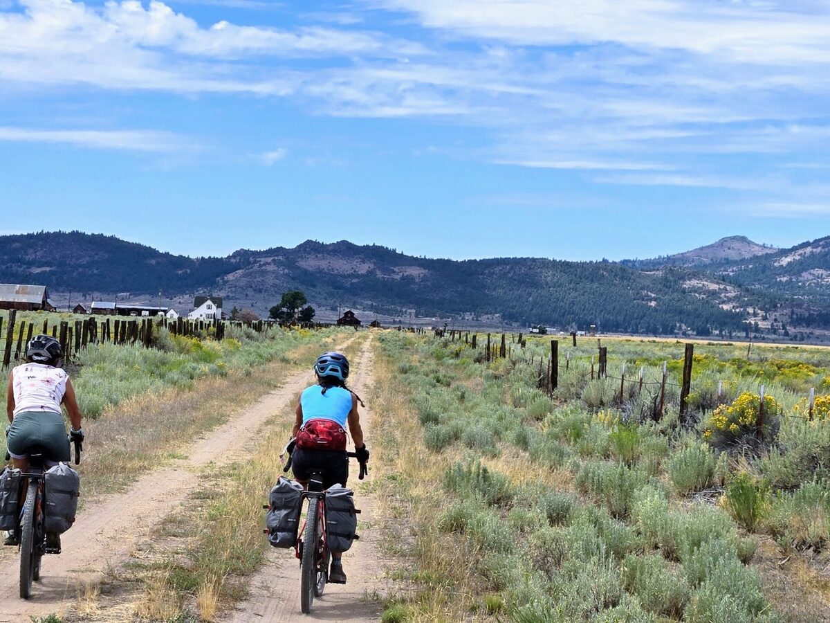 Bikepackers riding a gravel road through Sierra Valley toward Beckwourth Peak High Camp
