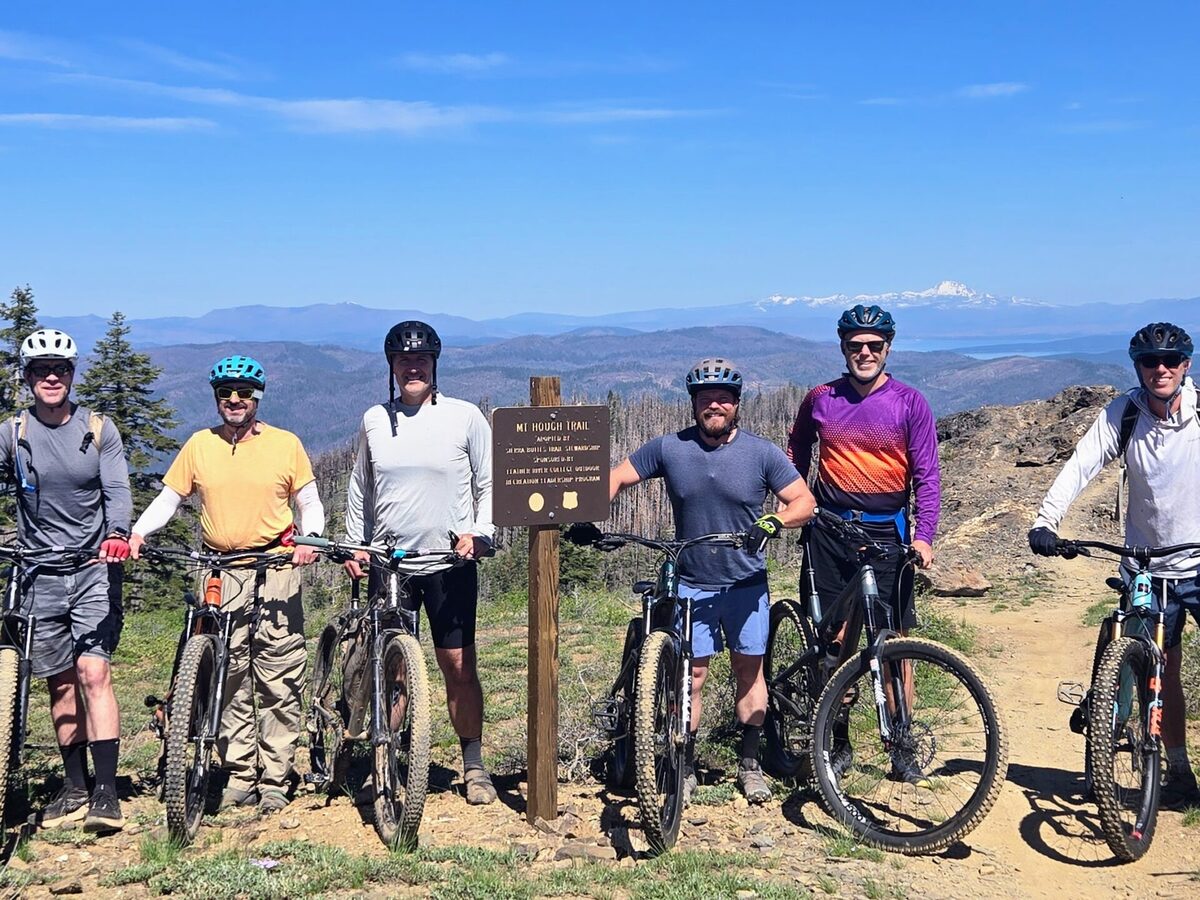Group of mountain bikers at the Mt. Hough Trail summit sign